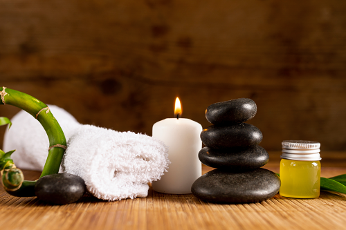 Arrangement of spa towel, stones, and bottle of oil on a table